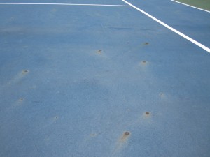 What causes rust spots on a tennis court
